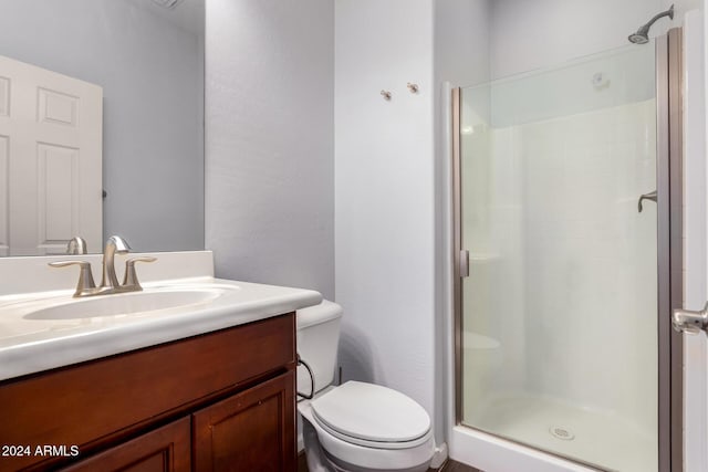 bathroom featuring vanity, toilet, and a shower with door