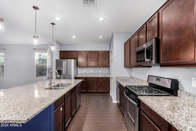 kitchen with appliances with stainless steel finishes, dark hardwood / wood-style flooring, light stone counters, sink, and decorative light fixtures