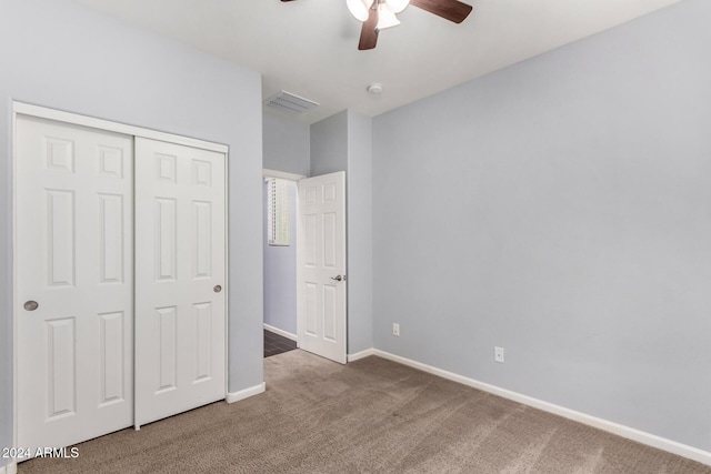 unfurnished bedroom with dark colored carpet, a closet, and ceiling fan