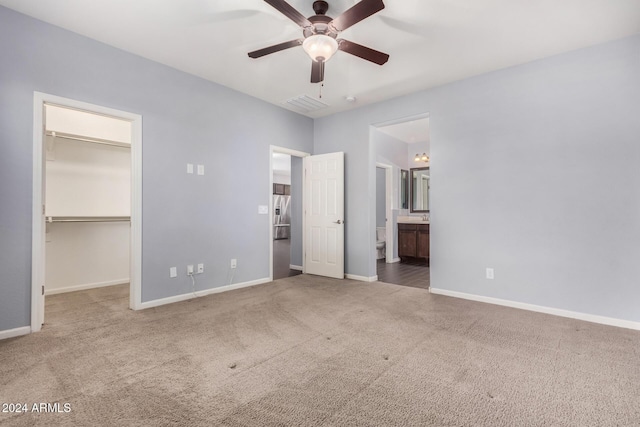 unfurnished bedroom with carpet, connected bathroom, a spacious closet, and ceiling fan