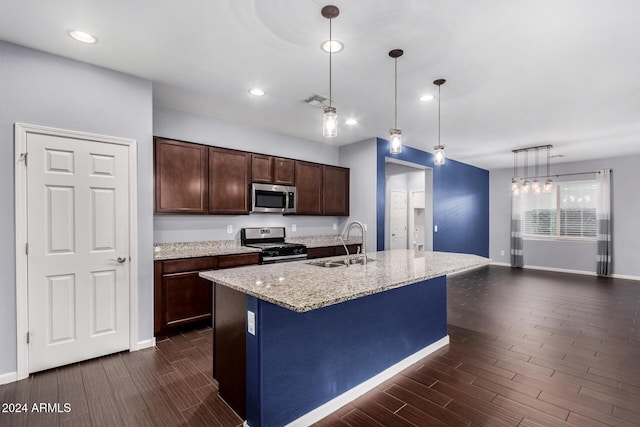 kitchen with sink, dark wood-type flooring, pendant lighting, a kitchen island with sink, and appliances with stainless steel finishes