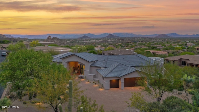 view of front facade featuring a mountain view, a tile roof, an attached garage, and stucco siding