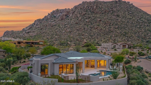back of house featuring a mountain view, a patio area, a jacuzzi, a fenced backyard, and stucco siding