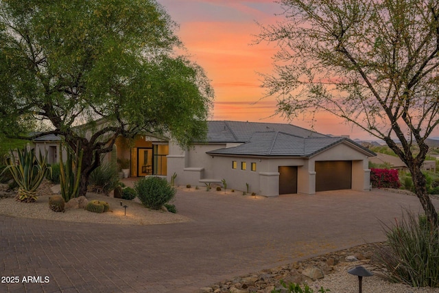 view of front of house with a garage, stucco siding, a tile roof, and decorative driveway