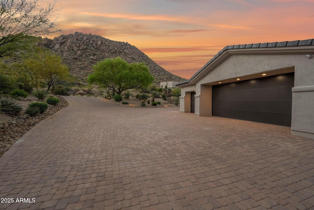exterior space featuring a garage, decorative driveway, stucco siding, and a mountain view