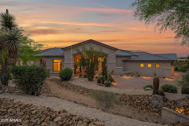 view of front of property featuring a patio, stucco siding, and a tile roof