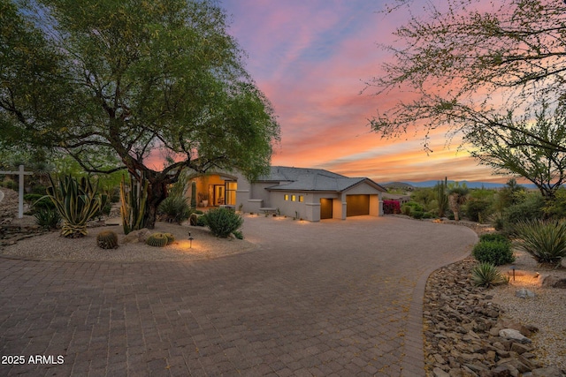 view of front facade featuring an attached garage, curved driveway, and stucco siding
