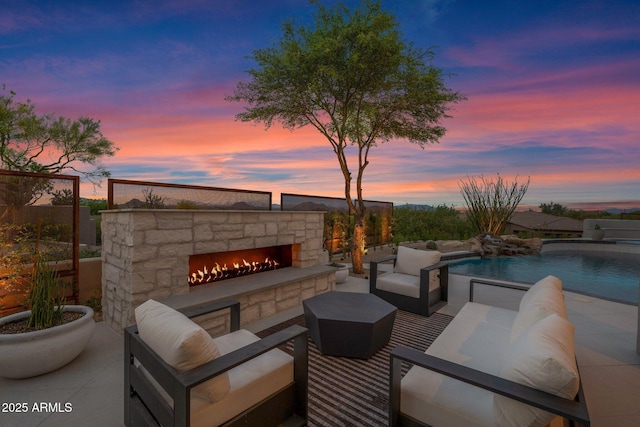 patio terrace at dusk with an outdoor living space with a fireplace