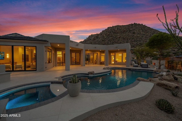 rear view of property with a patio area, an outdoor pool, an in ground hot tub, and stucco siding