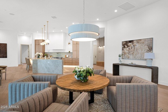 living room with recessed lighting, visible vents, baseboards, and light wood-style flooring