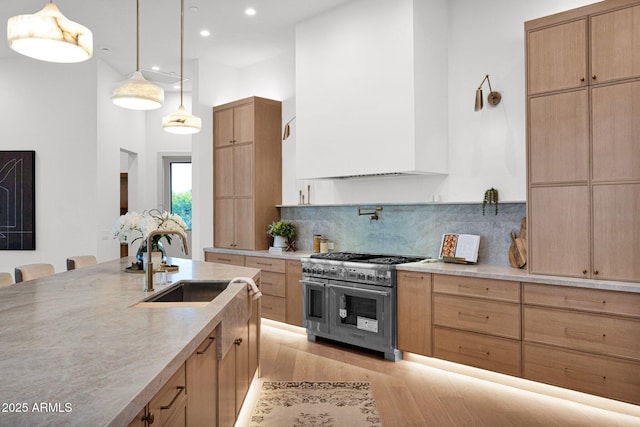 kitchen with a sink, light countertops, double oven range, and light wood-style flooring