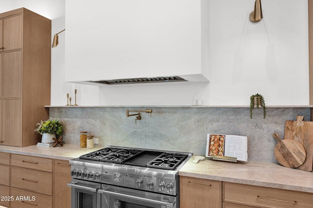 kitchen featuring light brown cabinets, tasteful backsplash, light countertops, and range with two ovens