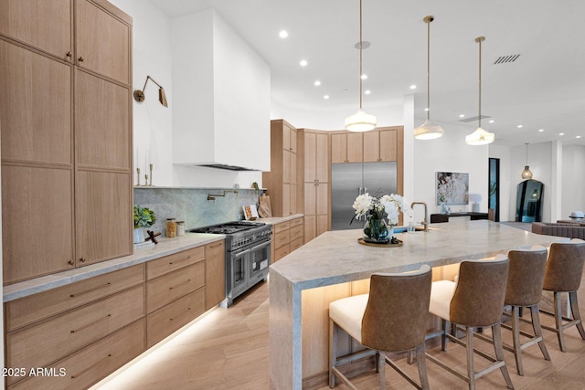 kitchen with tasteful backsplash, custom range hood, light brown cabinets, and stainless steel appliances