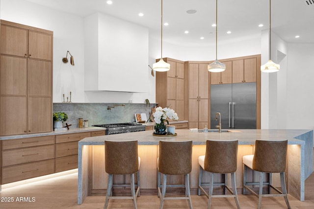 kitchen with modern cabinets, stove, light brown cabinets, backsplash, and built in fridge