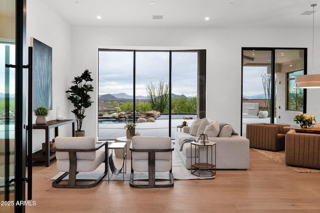 sitting room featuring wood finished floors, a mountain view, recessed lighting, and a wealth of natural light