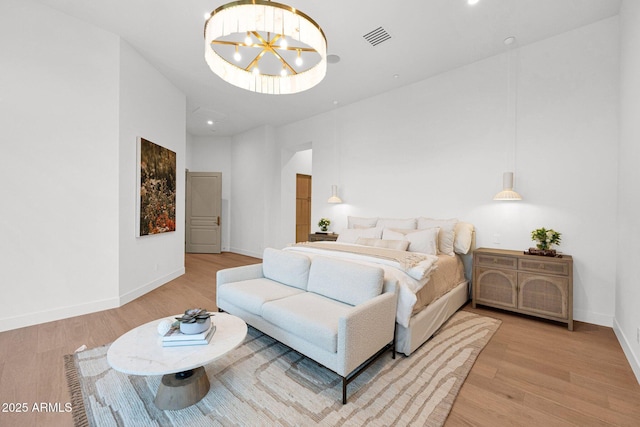 bedroom with light wood-style floors, a notable chandelier, visible vents, and baseboards