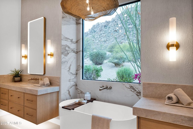 bathroom featuring a soaking tub, vanity, and a wealth of natural light
