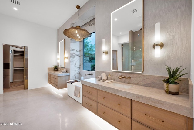 bathroom with a stall shower, two vanities, a sink, and visible vents
