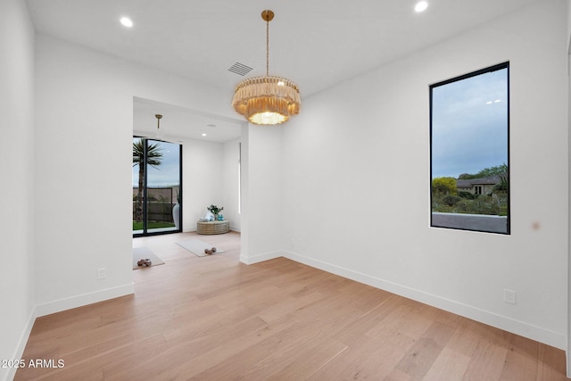empty room featuring wood finished floors, a notable chandelier, baseboards, and recessed lighting