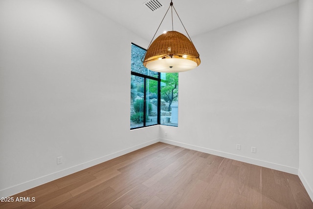 empty room with visible vents, baseboards, and wood finished floors