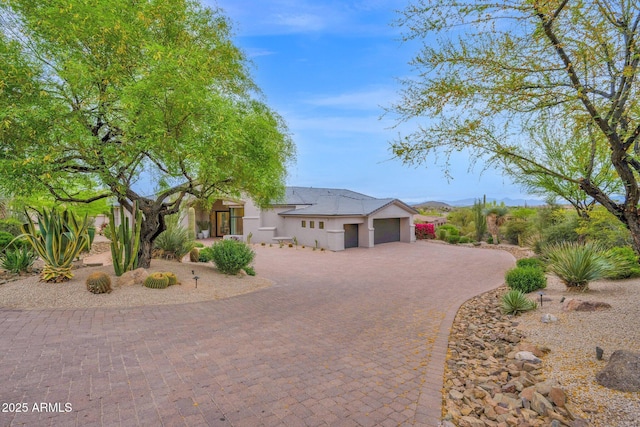 view of front of home with an attached garage, curved driveway, and stucco siding