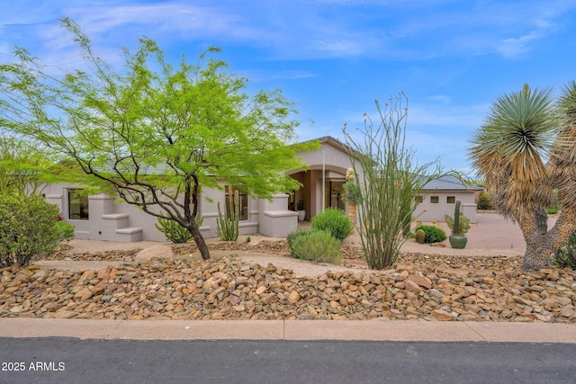 view of property hidden behind natural elements with stucco siding