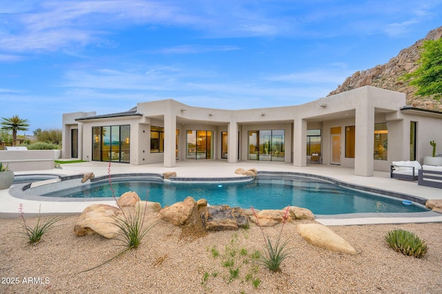 back of property featuring an outdoor pool, a patio, and stucco siding