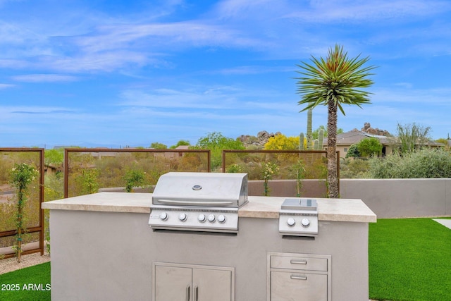view of patio / terrace featuring fence, a grill, and an outdoor kitchen