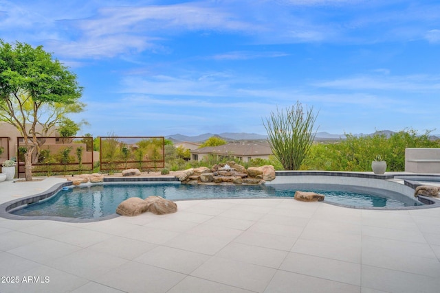 view of swimming pool featuring a patio, a pool with connected hot tub, fence, and a mountain view