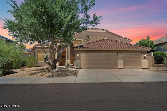 mediterranean / spanish house with a garage, concrete driveway, a tile roof, and stucco siding