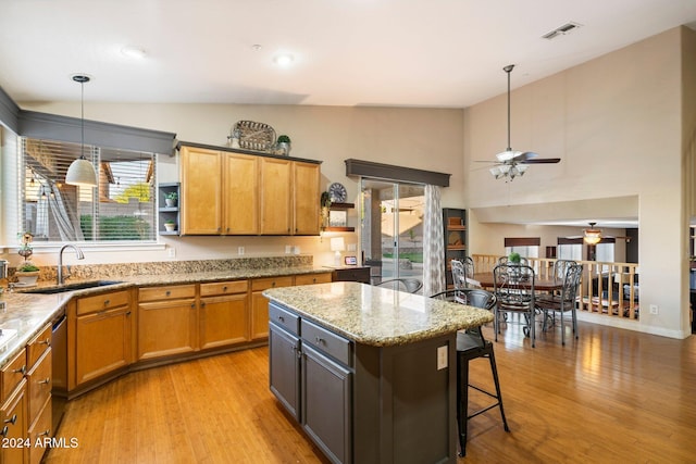 kitchen featuring light stone counters, pendant lighting, visible vents, and brown cabinets