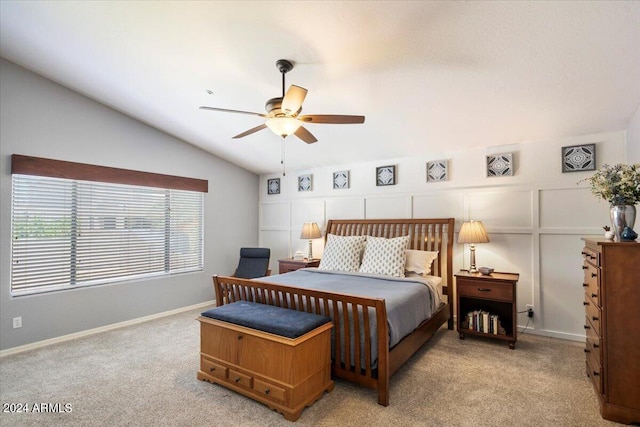 bedroom with vaulted ceiling, light carpet, a ceiling fan, and a decorative wall