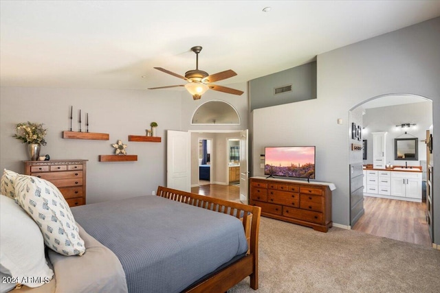 bedroom with arched walkways, light carpet, visible vents, vaulted ceiling, and ensuite bath