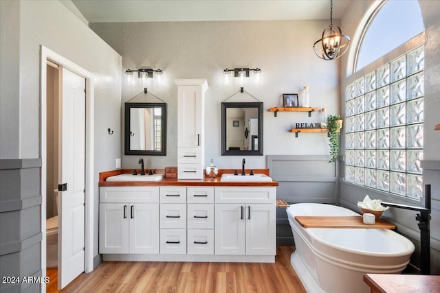 full bath featuring double vanity, an inviting chandelier, a sink, and wood finished floors