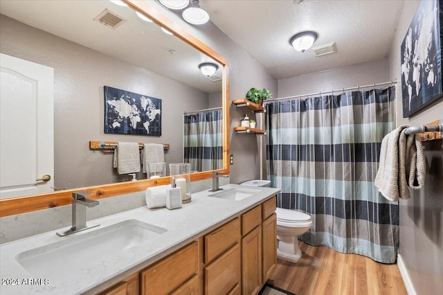 bathroom with wood finished floors, a sink, and visible vents