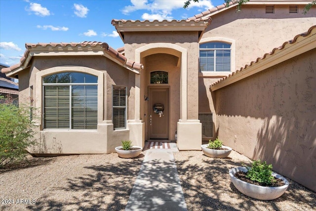 entrance to property featuring a tile roof and stucco siding