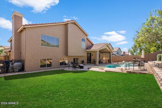 rear view of property featuring a fenced in pool, a yard, and a patio area