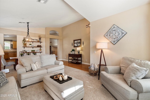 living area featuring lofted ceiling, visible vents, and baseboards