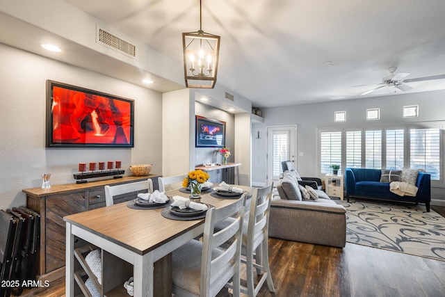 dining area with a healthy amount of sunlight, ceiling fan with notable chandelier, and dark hardwood / wood-style flooring