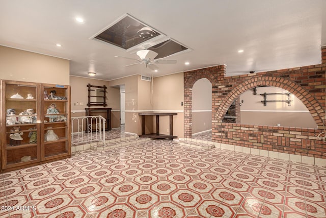 living room with ceiling fan and brick wall