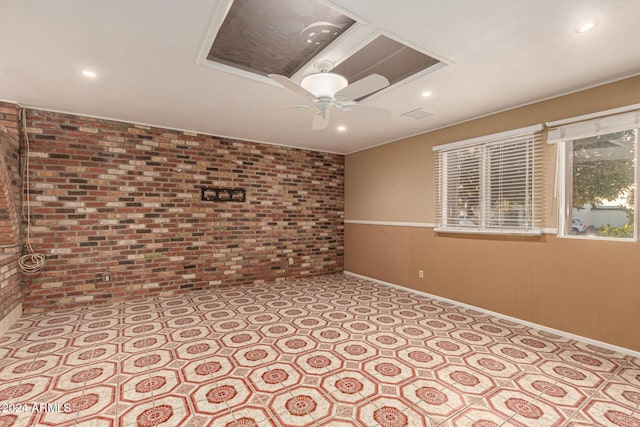 spare room featuring ceiling fan and brick wall