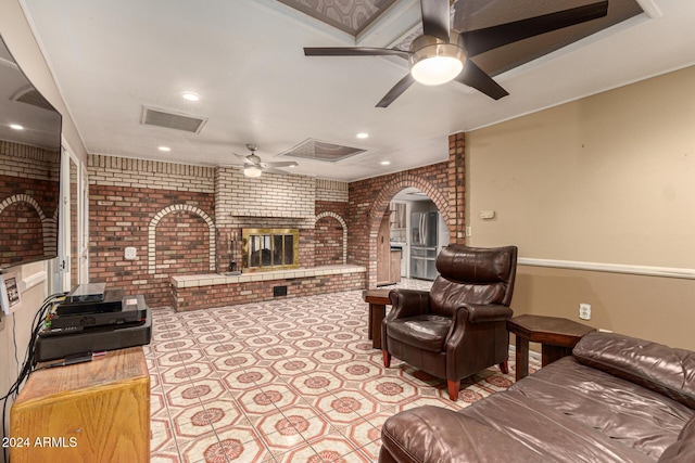 living room featuring ceiling fan, brick wall, and a brick fireplace