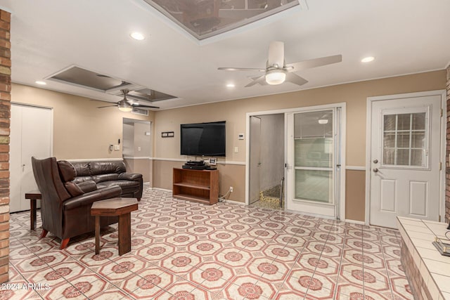 living room with a raised ceiling and ceiling fan