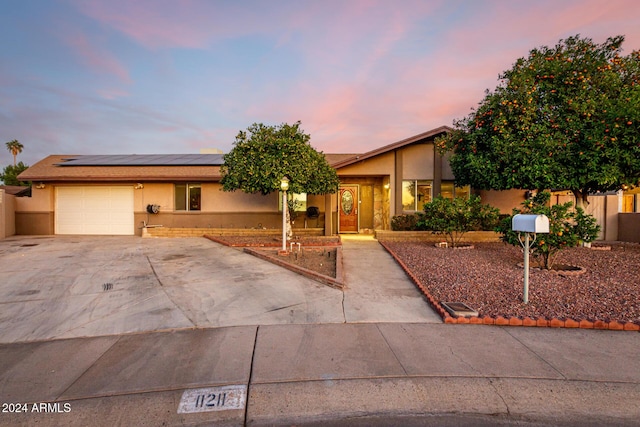 ranch-style home featuring solar panels and a garage