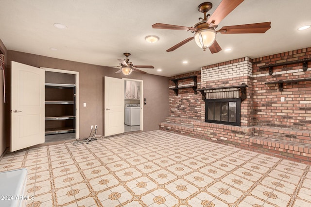 unfurnished living room featuring a fireplace, washer / clothes dryer, ceiling fan, and brick wall