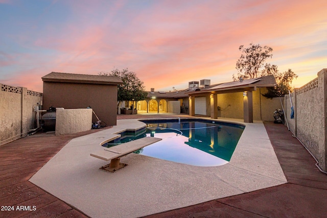 pool at dusk with a diving board and a deck