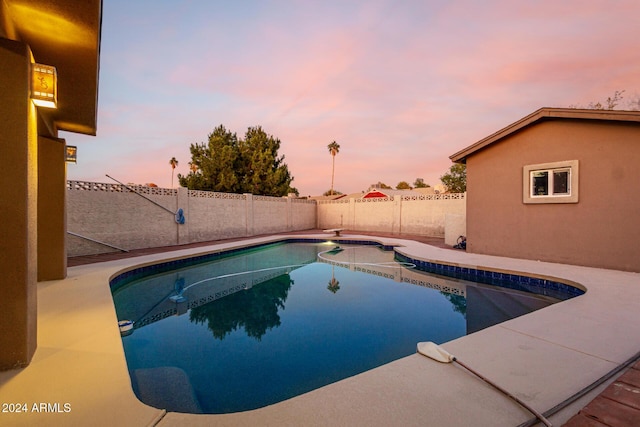 pool at dusk featuring a diving board