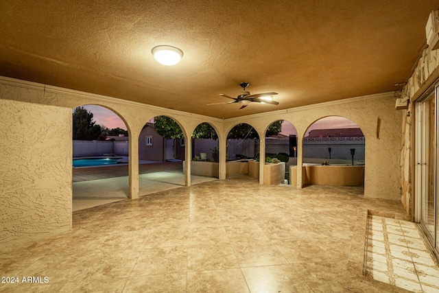 patio terrace at dusk featuring ceiling fan and a pool