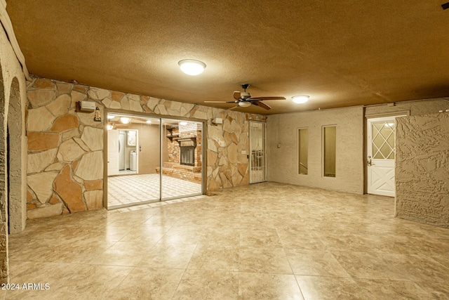 basement featuring ceiling fan, washer / dryer, and a brick fireplace