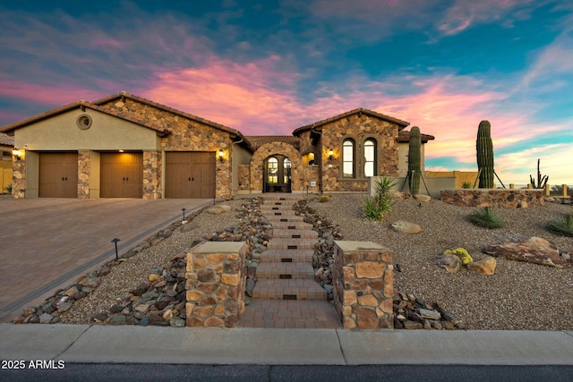 view of front of property with a tile roof, stucco siding, decorative driveway, a garage, and stone siding